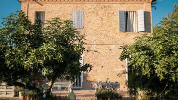 Traditional brick building surrounded by lush greenery and a charming outdoor seating area.