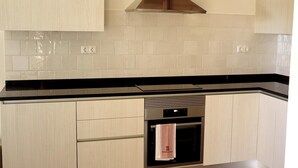 Een keuken met witte kastjes, een zwart aanrecht en een roestvrijstalen afzuigkap.