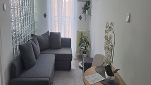 Una sala de estar moderna con un sofá seccional gris, una mesita redonda con un florero y un menú, y una orquídea en maceta.