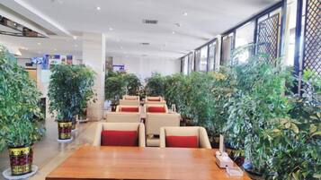 A restaurant with multiple tables and chairs, surrounded by potted plants.