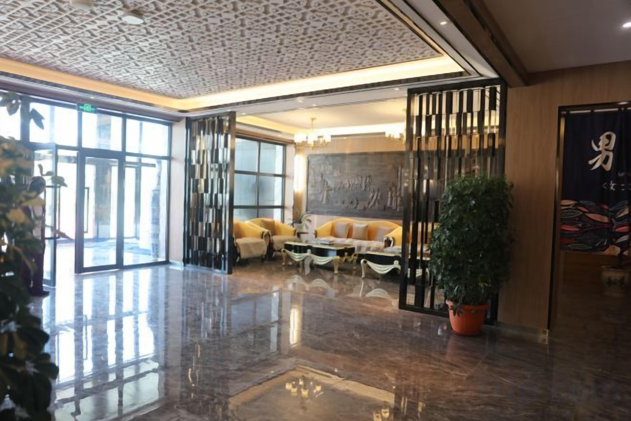 Un hall d’entrée avec une cloison en verre, un espace salon et une plante en pot.
