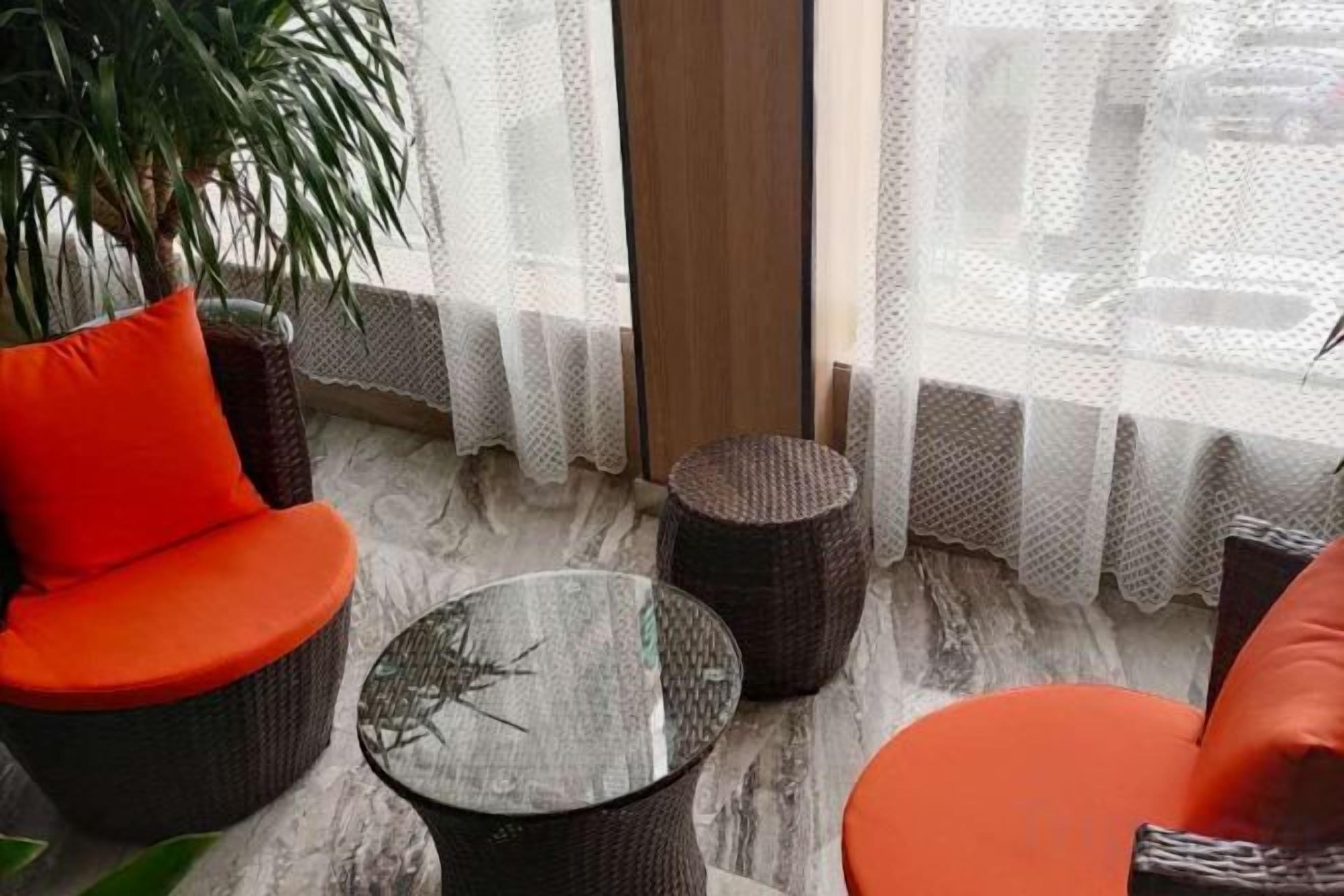 A seating area with wicker furniture and a glass table, near a window with sheer curtains.