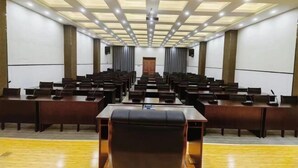 A conference room with rows of tables and chairs, a podium, and a ceiling with recessed lighting. - Tibet Ali Hotel (Gar County)