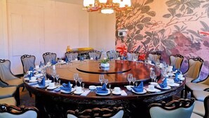 A round table set for a meeting with chairs around it, a chandelier above, and a floral wall mural.