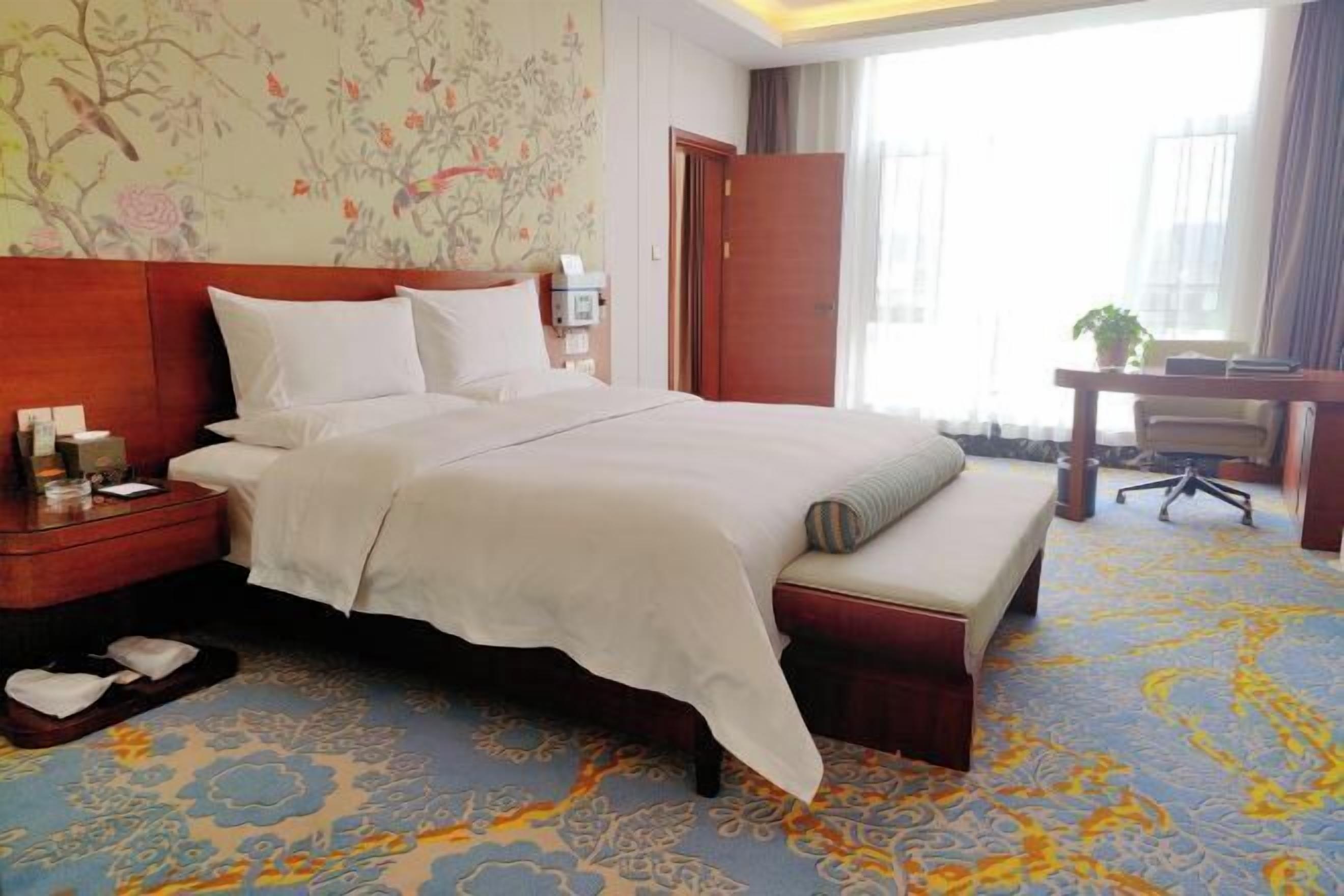 A hotel room with a large bed, a desk, and a chair.
