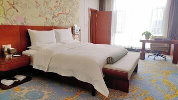 A hotel room with a large bed, a desk, and a chair.