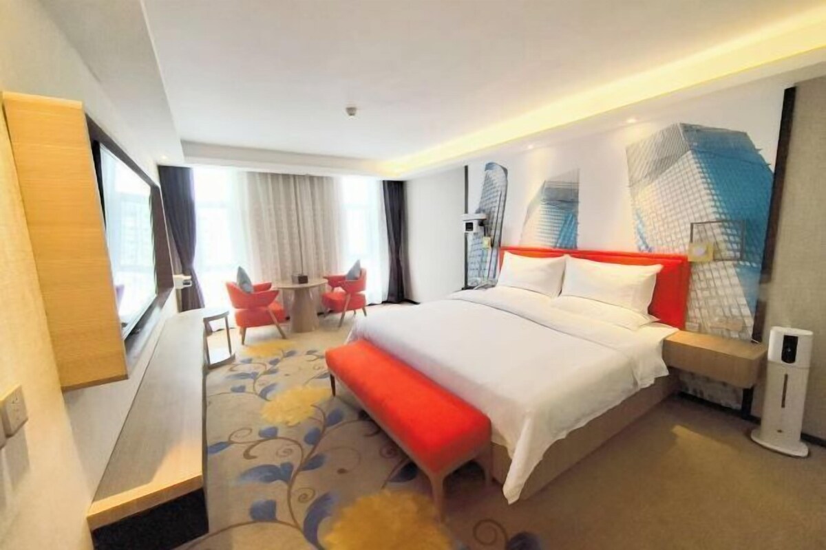 A modern hotel room with a large bed, a desk, and a chair.