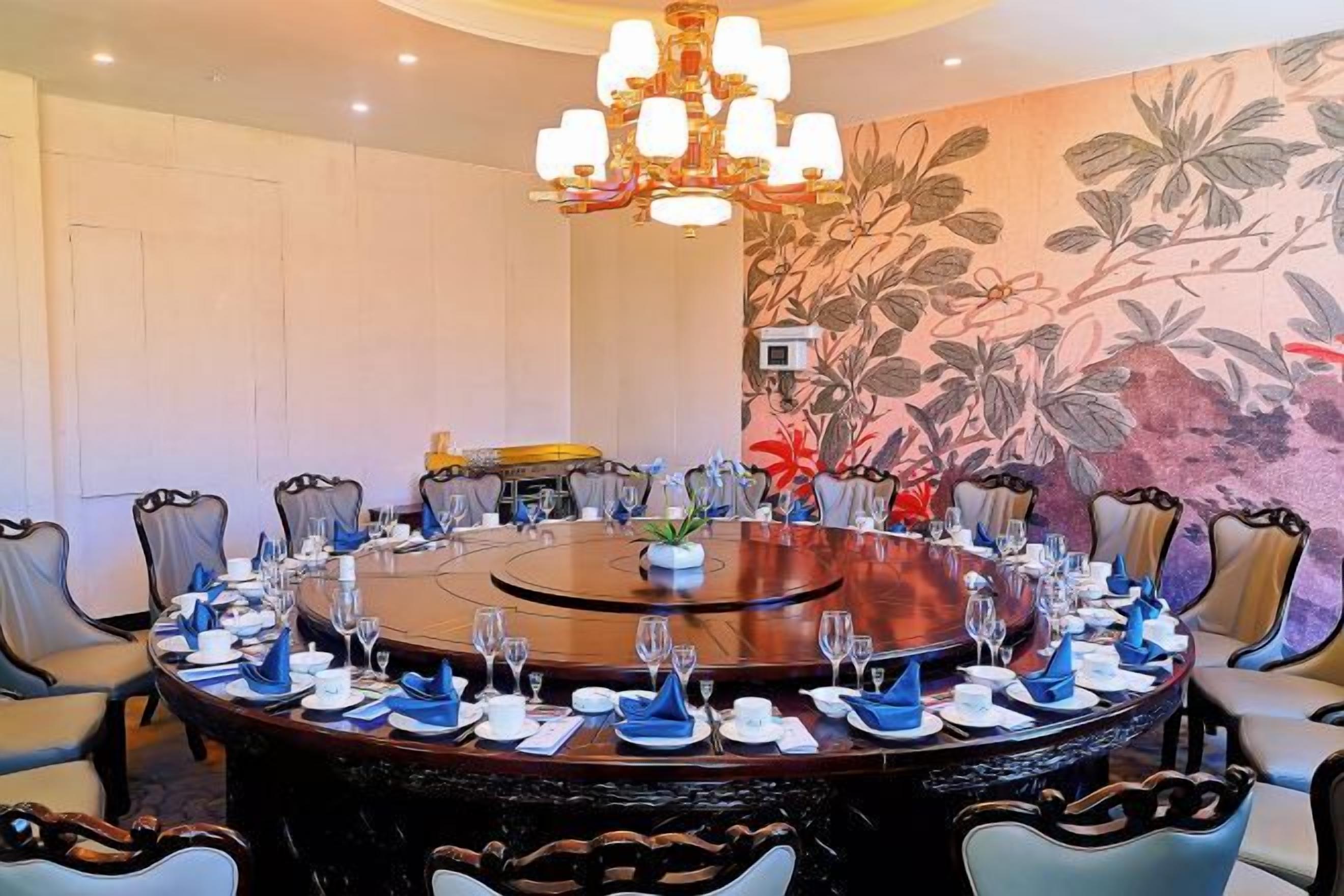 A conference room with a round table, chairs, and a chandelier.
