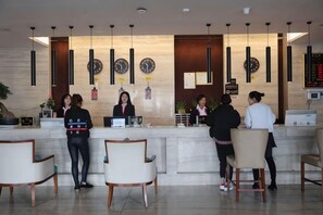 A hotel reception area with a marble counter, several receptionists, and a modern interior design. - Tibet Ali Hotel (Gar County)