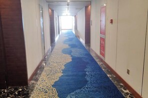 A hotel hallway with a carpeted floor, doors on both sides, and a light source at the end. - Tibet Ali Hotel (Gar County)