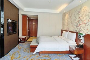 A hotel room with a large bed, a bedside table, a TV, and a floral wallpaper. - Tibet Ali Hotel (Gar County)