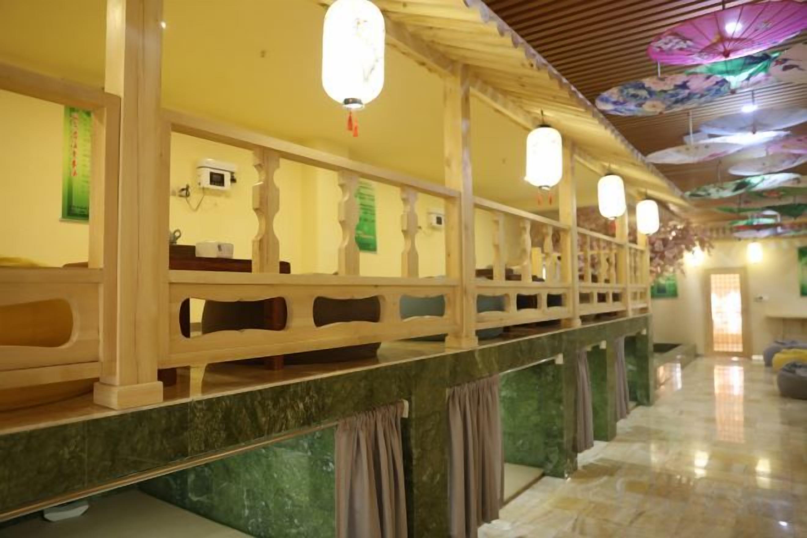 Un couloir d’hôtel avec un sol en marbre, des rampes en bois et des lanternes suspendues.