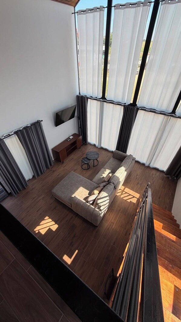 Un intérieur moderne avec un canapé d’angle, un téléviseur à écran plat et une petite table ronde.