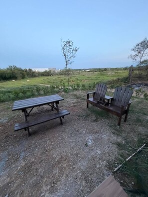 Un espace extérieur aménagé avec une table de pique-nique et deux fauteuils Adirondack.