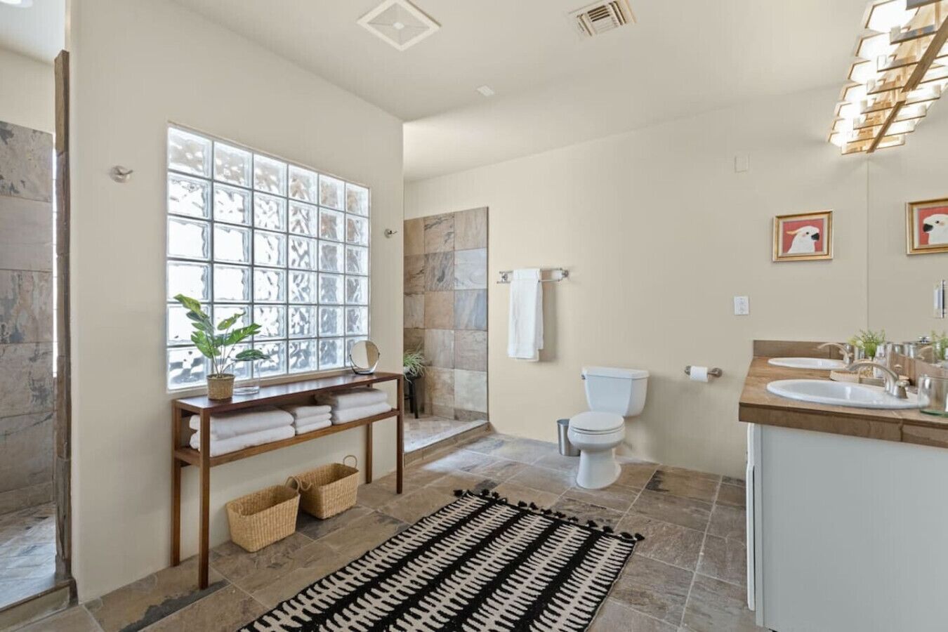 A bathroom with a large window, a shower, a toilet, and a sink area.