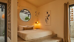 A bedroom with a bed, a round mirror, a wall clock, and a window with curtains. - ROSA by DW (San Juan)