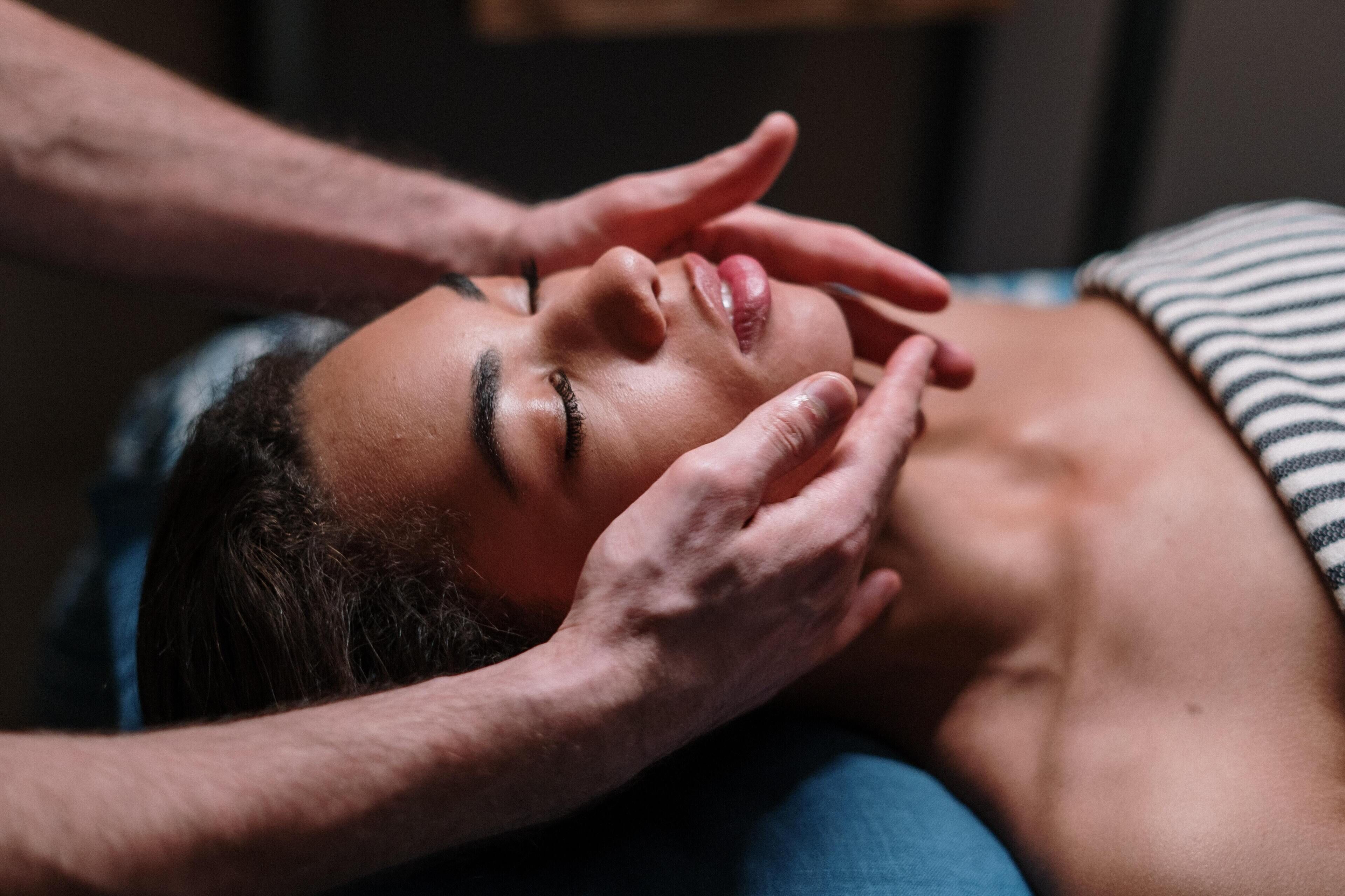 En person ligger ner med händerna över ansiktet, eventuellt under en massage.