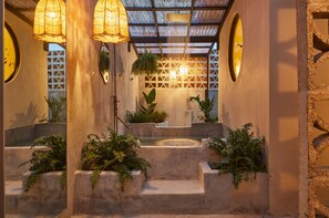 Un intérieur moderne avec un plafond au design géométrique, des marches en béton et des plantes en pot.