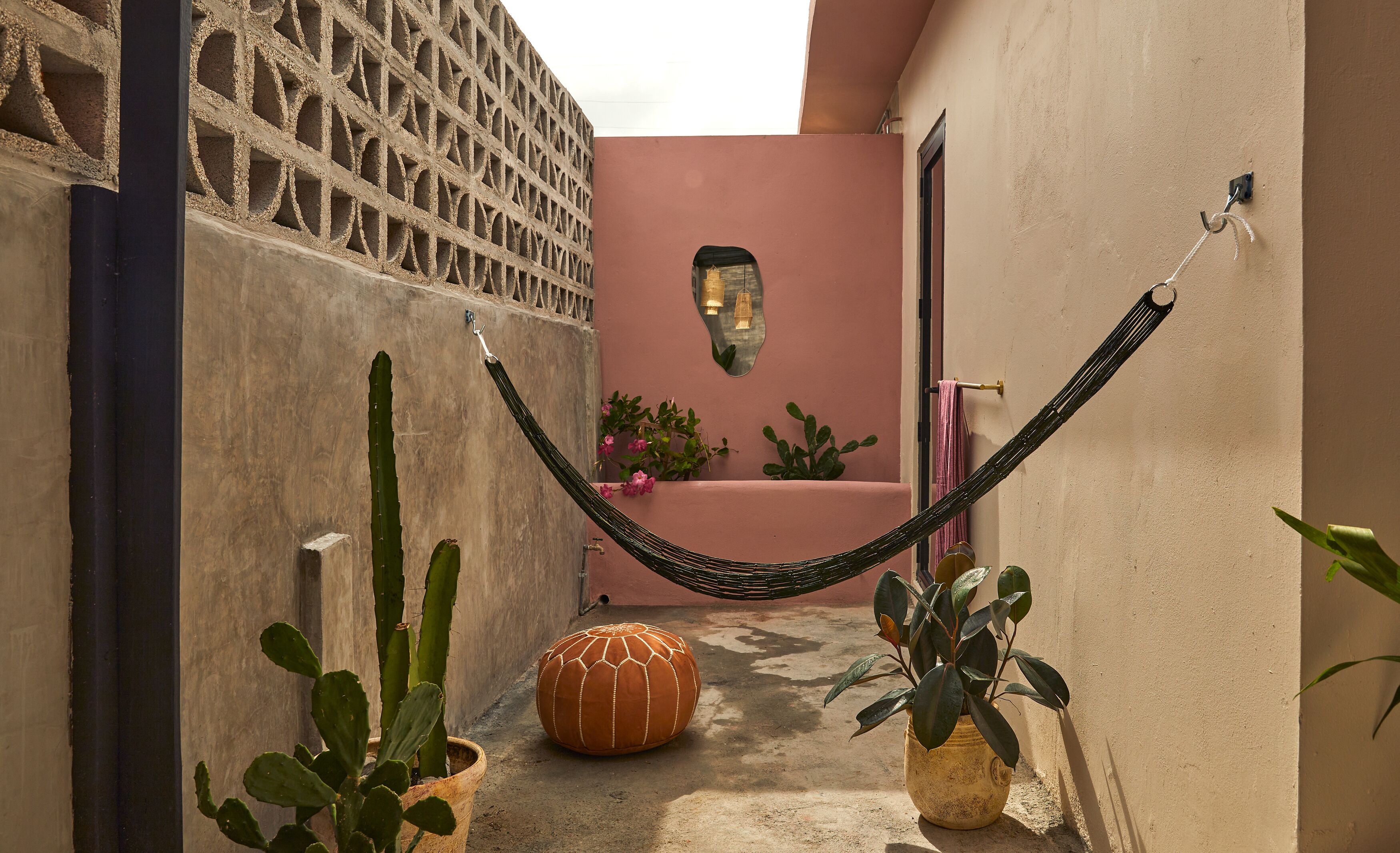 A narrow alleyway with a hammock, cacti, and a potted plant.