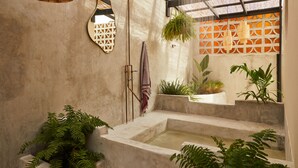 A modern bathroom with a concrete floor, a freestanding bathtub, and a large window with a bamboo ceiling. - ROSA by DW (San Juan)