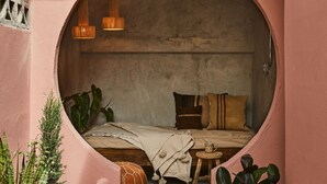A cozy circular room with a bed, pillows, a small table, and hanging lights. - ROSA by DW (San Juan)