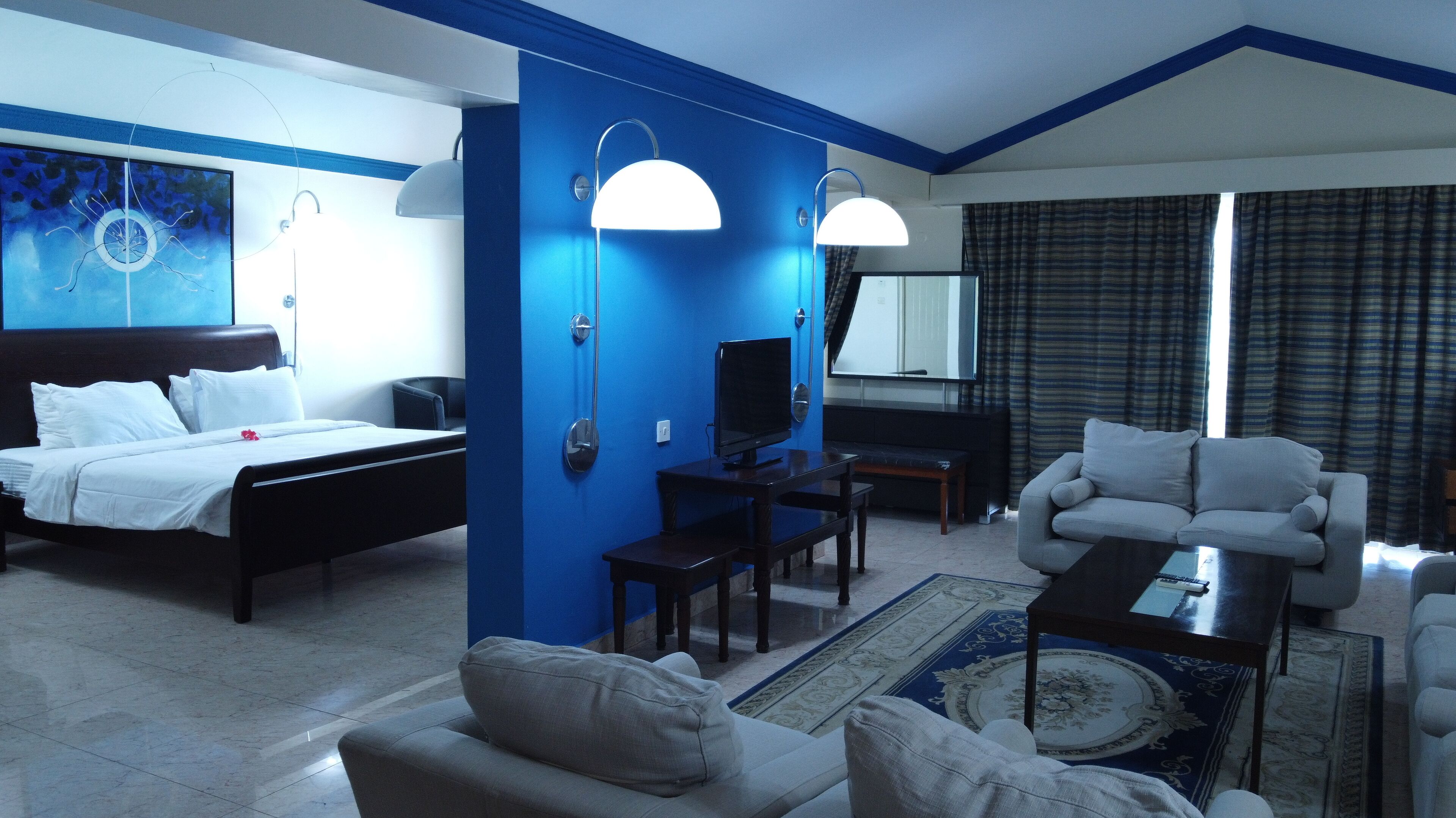 A hotel room with a bed, a desk, a television, a sofa, and a coffee table.