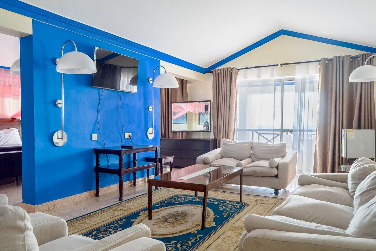 A living room with a blue accent wall, a flat-screen TV, a coffee table, and a sofa.