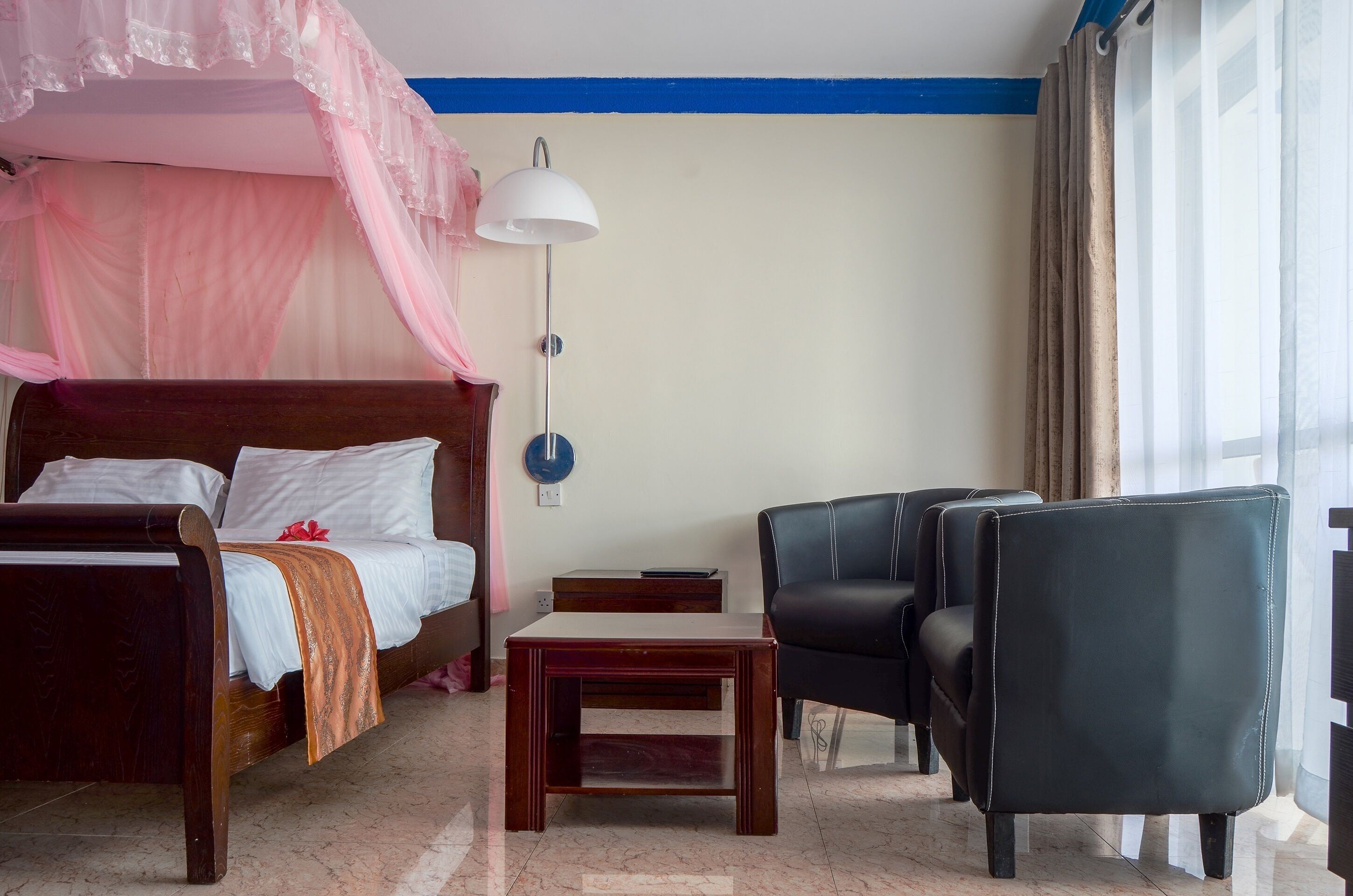 Een slaapkamer met een bed, nachtkastje, lamp en een stoel.