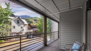 Ein Balkon mit Bergblick, ein Holzhaus und eine Straße.