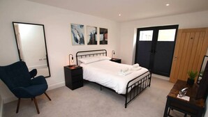 A bedroom with a bed, bedside tables, a chair, a desk, and a large mirror.