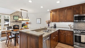 A modern kitchen with granite countertops, wooden cabinets, stainless steel appliances, and a fireplace. - Slopeside Paradise Penthouse At Lift 7, Views, Fireplace, Deck, Hot Tub 3 Bedroom Condo by RedAwning (Telluride)