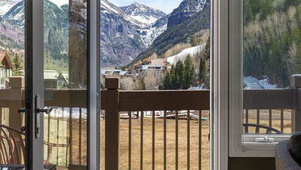 A balcony with a view of a mountainous landscape, a wooden chair, and a table. - Slopeside Paradise Penthouse At Lift 7, Views, Fireplace, Deck, Hot Tub 3 Bedroom Condo by RedAwning (Telluride)