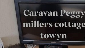 A television on a wooden cabinet with a remote control and a DVD player. - Beautiful 2-bed Caravan in Abergele Town (Abergele)