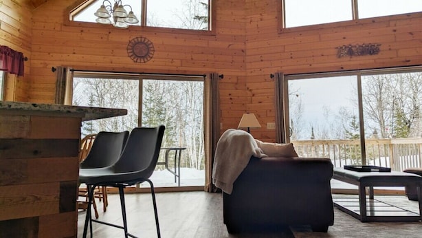 Une pièce spacieuse avec un plafond haut, de grandes fenêtres, un coin salon confortable et un décor intérieur en bois.