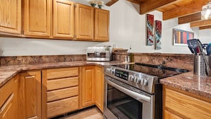 A kitchen with wooden cabinets, a built-in oven, and a granite countertop. - Riverside Dream! Quiet Spot W Deck, 5 Min Walk To Gondola & Main St. 2 Bedroom Condo by RedAwning (Telluride)