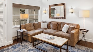 A living room with a sectional sofa, a coffee table, a side table, a lamp, and a large mirror on the wall. - Lift 7 Ski In/out Hot Tub, Ski Locker, Garage Parking + Shuttle To Gondola 2 Bedroom Condo by RedAwning (Telluride)