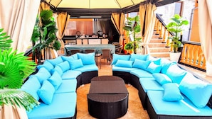 A curved sectional sofa with light blue cushions, a round coffee table, and potted plants. - Sea Marble Villa Studio (Sozopol)