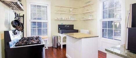 A compact kitchen with a gas stove, white cabinetry, and built-in shelves.