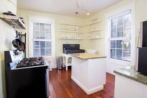 Compact kitchen with central island, gas stove, and shelf unit.