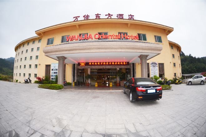 A hotel with a curved facade, a signboard with Chinese characters, and a car parked in front.
