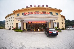 Un hotel con fachada curva, un cartel con caracteres chinos y un coche estacionado adelante.