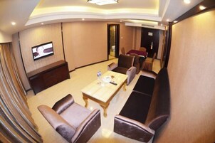 Una habitación de hotel con un televisor montado en la pared, un sofá, una mesa de comedor y una zona de comedor separada.