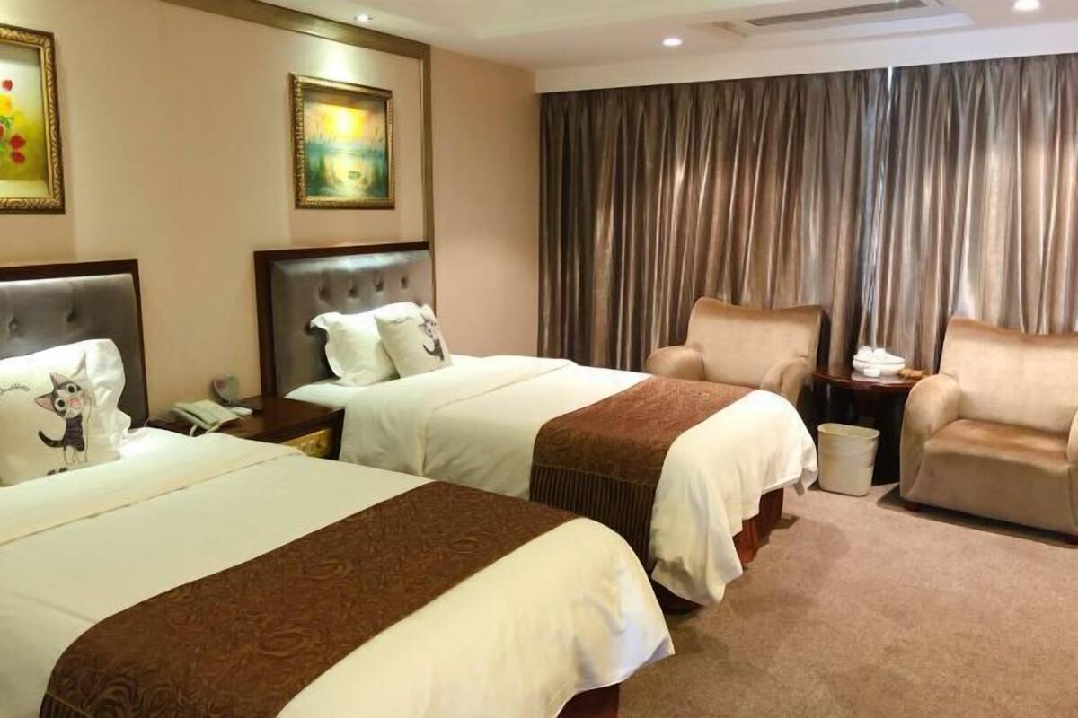 A hotel room with two beds, a sofa, a nightstand, and a curtain.