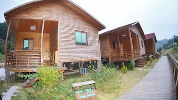 A row of wooden cabins with external staircases, a wooden boardwalk, and a signboard.