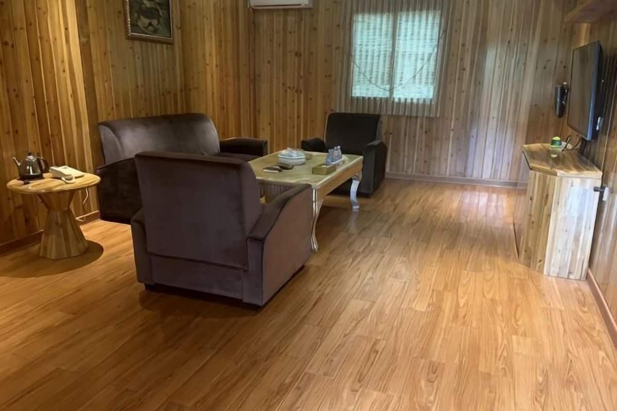 A wooden-paneled room with a sofa, chairs, a coffee table, and a television.