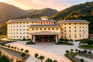 A hotel with a central entrance, multiple floors, and a parking area.