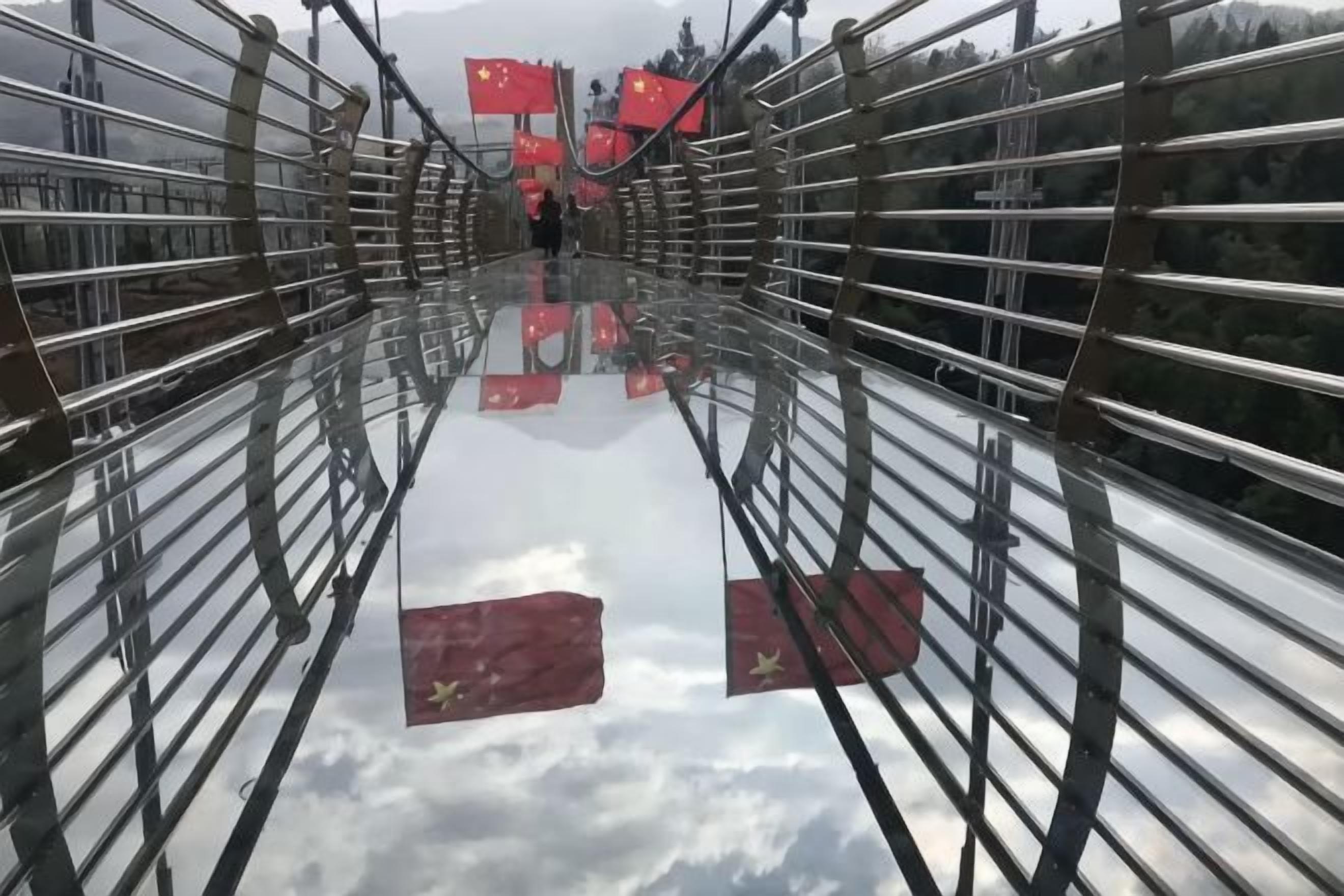 A suspension bridge with metal railings and red flags.