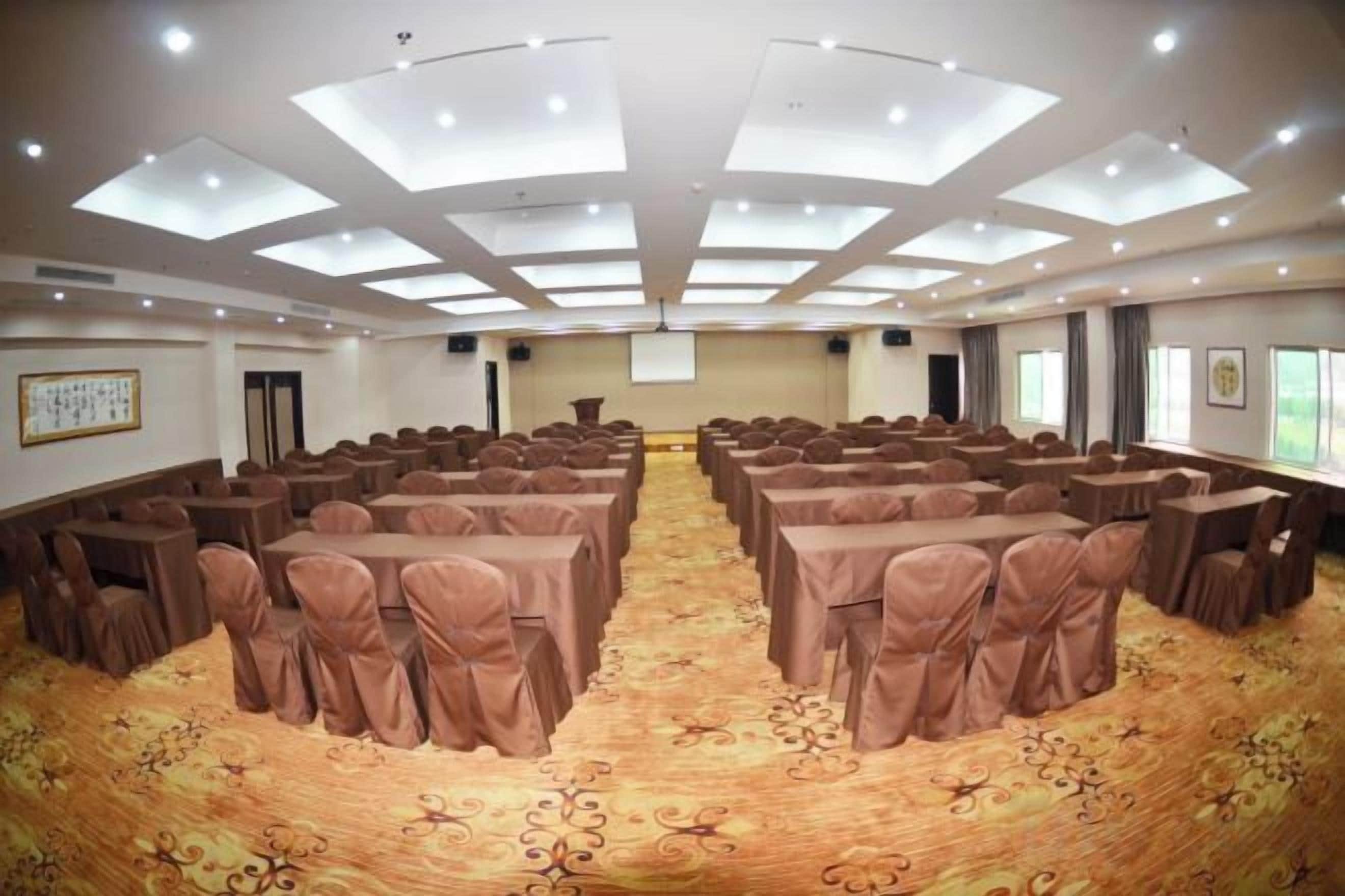 Un salón de conferencias con techo alto, varias mesas y sillas dispuestas para reuniones.