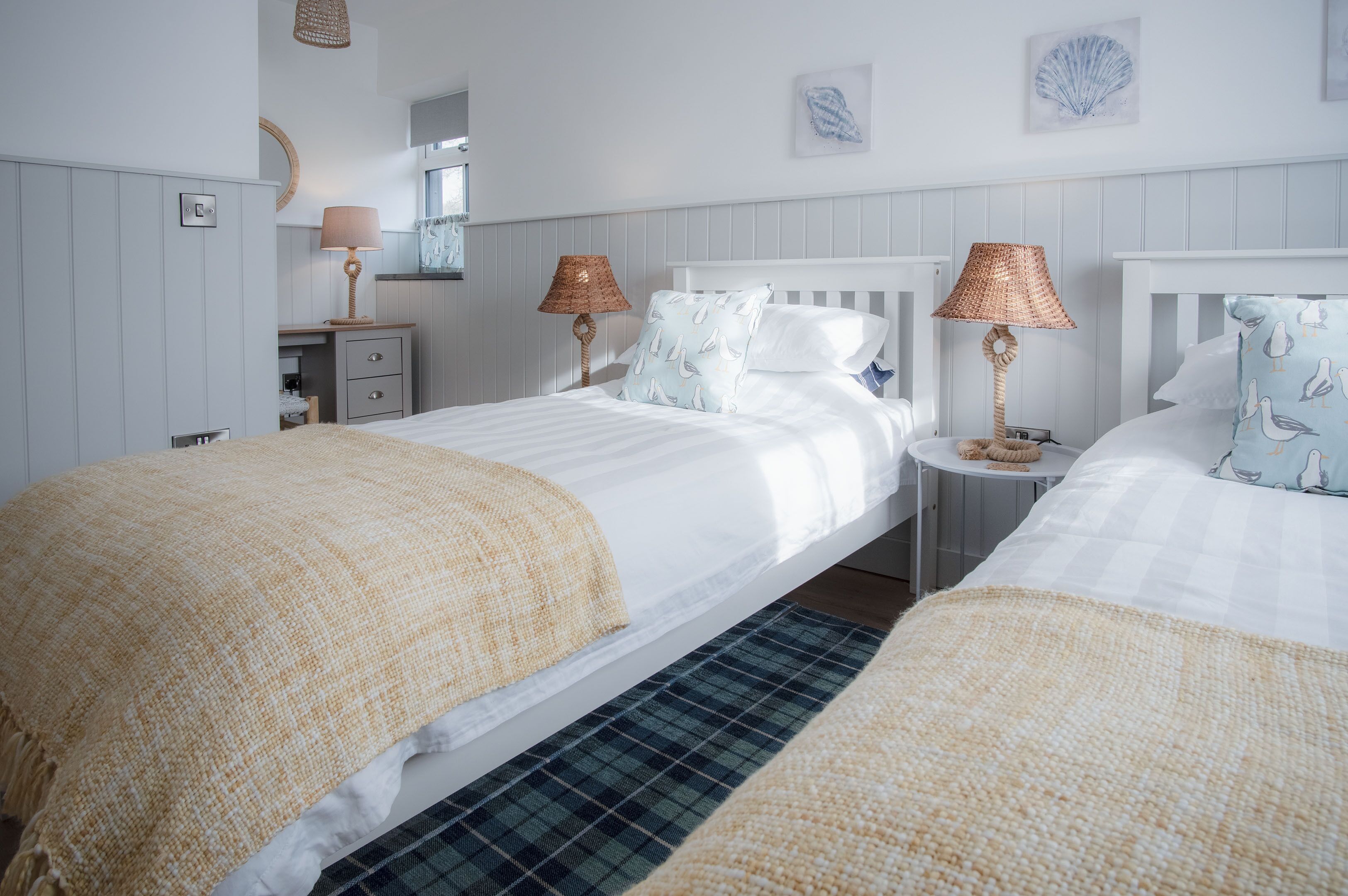 Une chambre d’hôtel avec deux lits, chacun doté d’une tête de lit blanche, d’une table de chevet avec une lampe et d’un petit bureau avec une chaise.