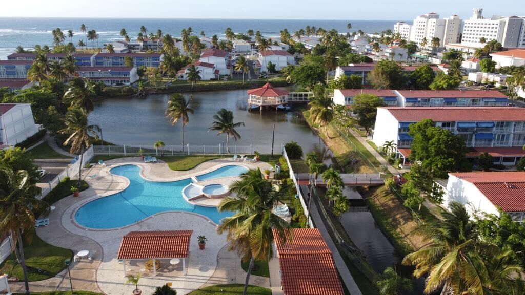 Een resort met een groot zwembad, palmbomen en uitzicht op de oceaan.